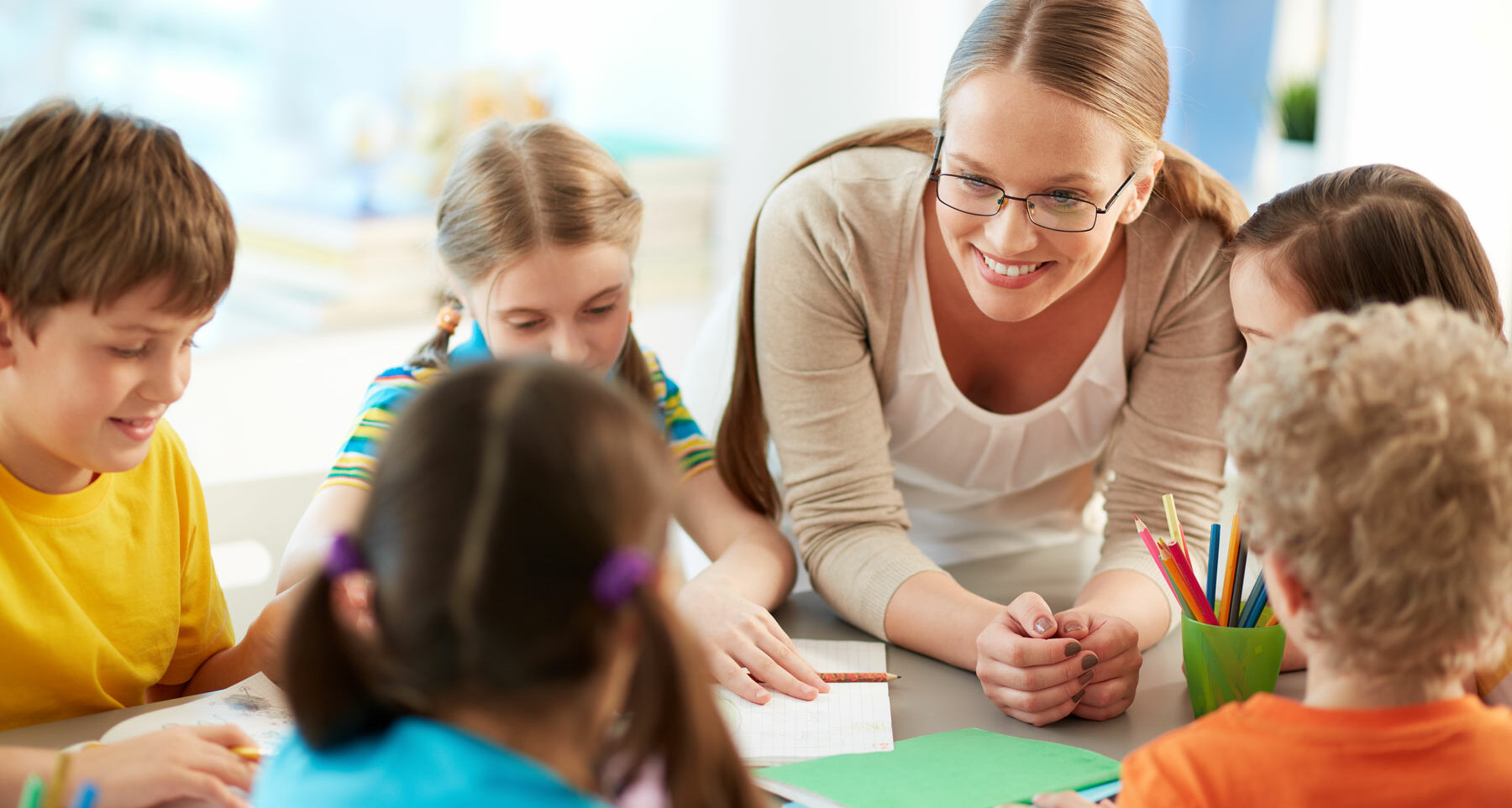 A smiling teacher checks in with her reading intervention group